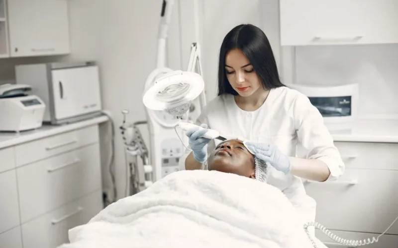Aesthetician providing a rejuvenating facial treatment to a client in a modern spa clinic setup.