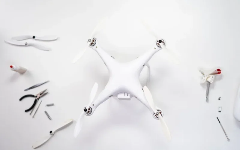 Overhead view of a drone being assembled with various tools on a white background.