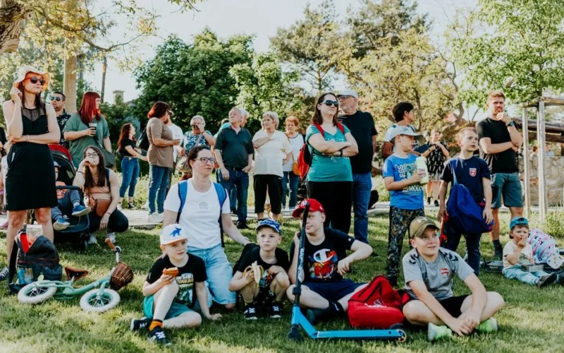 A diverse group of people enjoying a sunny day at an outdoor community event in a park setting.